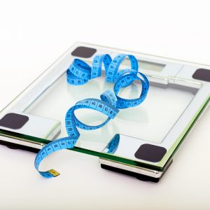 blue-tape-measuring-on-clear-glass-square-weighing-scale-53404